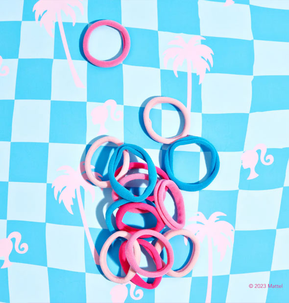 Collection of pink and blue fabric hair ties on a blue checkered Barbie logo surface