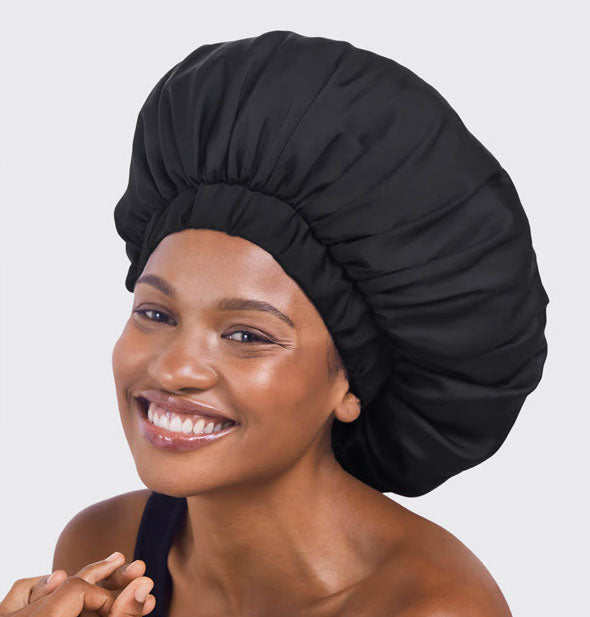 Smiling model wears a black XL Satin Bonnet over hair