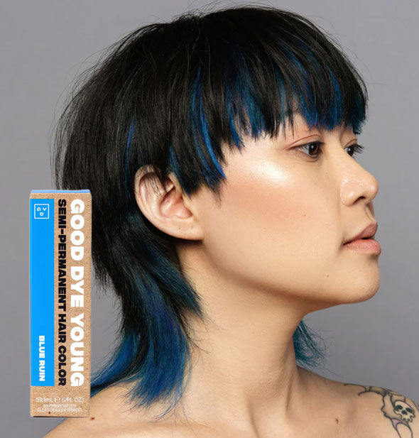 Model wears blue streaks in dark hair; box of Good Dye Young Semi-Permanent Hair Color in shade Blue Ruin is inset at bottom left