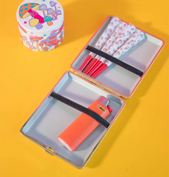 Opened case holds rolled cigarettes and an orange lighter under interior black elastic straps