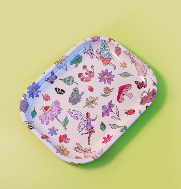 Rectangular white tray on a green backdrop features rounded corners and all-over illustrations of flowers, fairies, mushrooms, frogs, snails, leaves, rabbits, insects, butterflies, and more