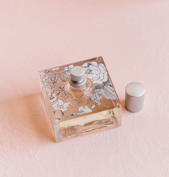 Stout square glass Lolla Classic Petal perfume bottle with silver cap removed features a delicate black and white floral motif
