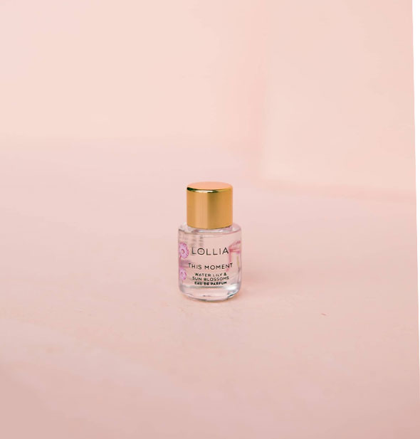Mini cylindrical glass bottle of Lollia: This Moment Water Lily & Sun Blossoms Eau de Parfum with pink floral motif and gold cap