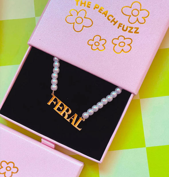 Closeup of the gold Feral nameplate pearl necklace in gift box
