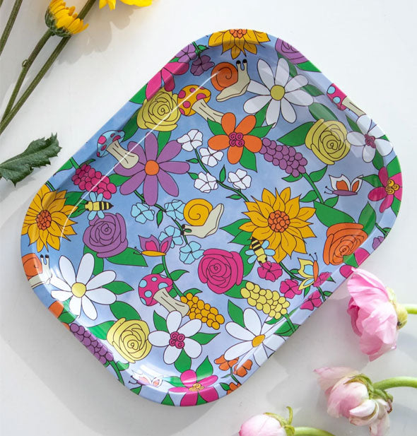 Rectangular blue tray with rounded corners features colorful print of flowers, mushrooms, snails, and butterflies