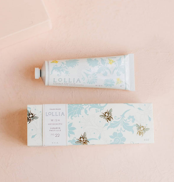 White tube and box of Lollia Wish Handcreme both feature blue floral patterning with gold bee accents