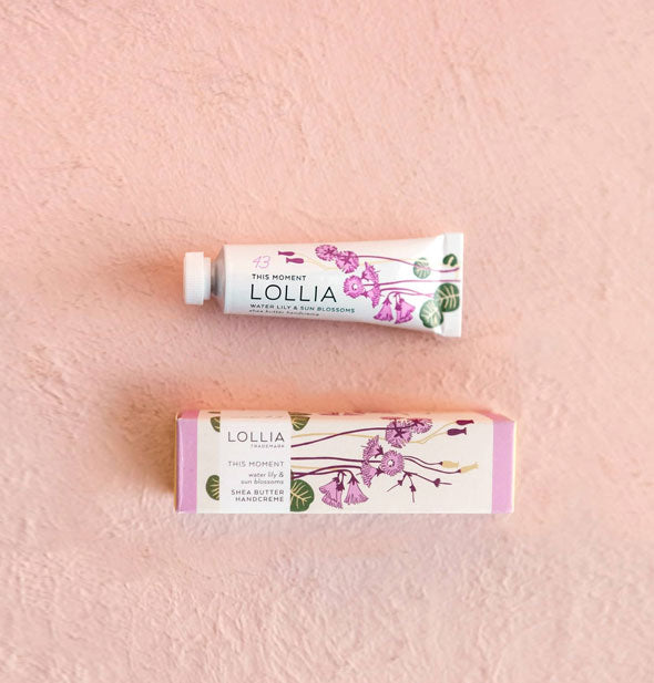 Mini white tube and box of Lollia This Moment Water Lily & Sun Blossoms Shea Butter Handcreme with purple, green, and gold florals and leaves designs