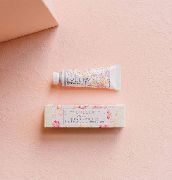 Mini white tube and box of Lollia Breathe Handcreme both feature pink and gold floral patterning