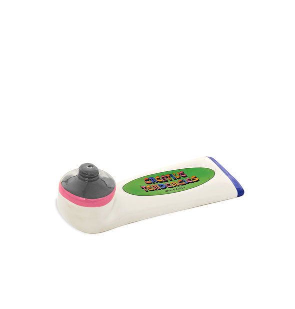 Ceramic incense holder is designed and painted to resemble a white tube of paint with pink and blue stripes and a green label that says, "Creative Tendencies" in multicolored lettering