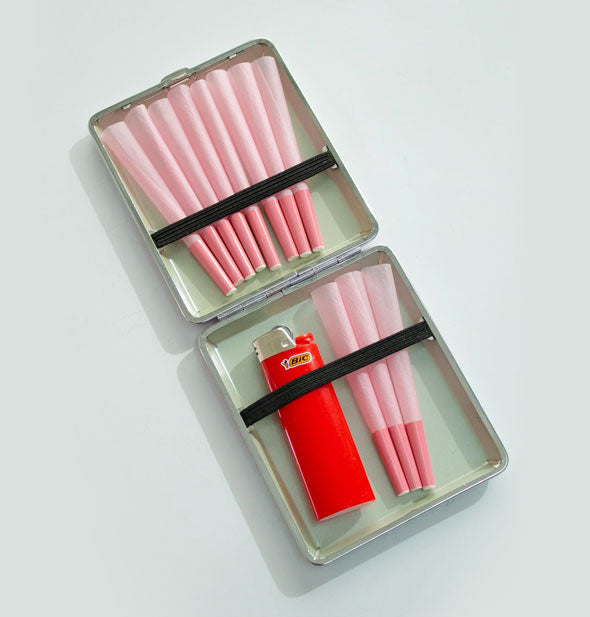 Opened cigarette case holds pink rolls and a red lighter under black elastic straps