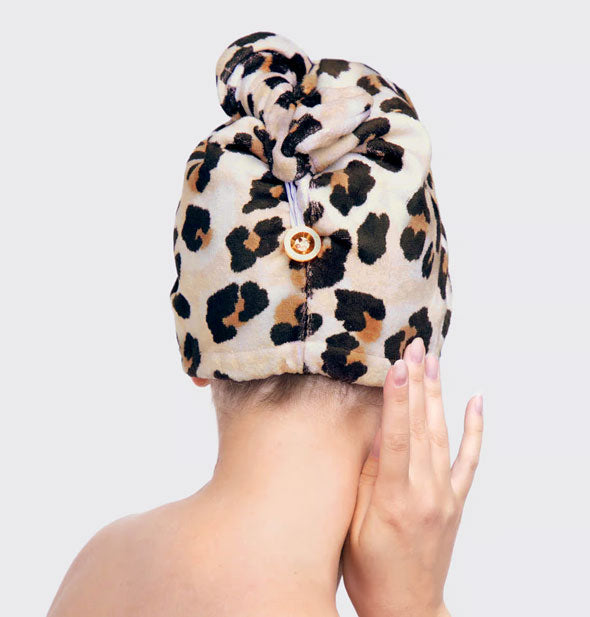 Model wearing leopard print Microfiber Hair Towel with face turned away from the camera to show button and loop detail in back