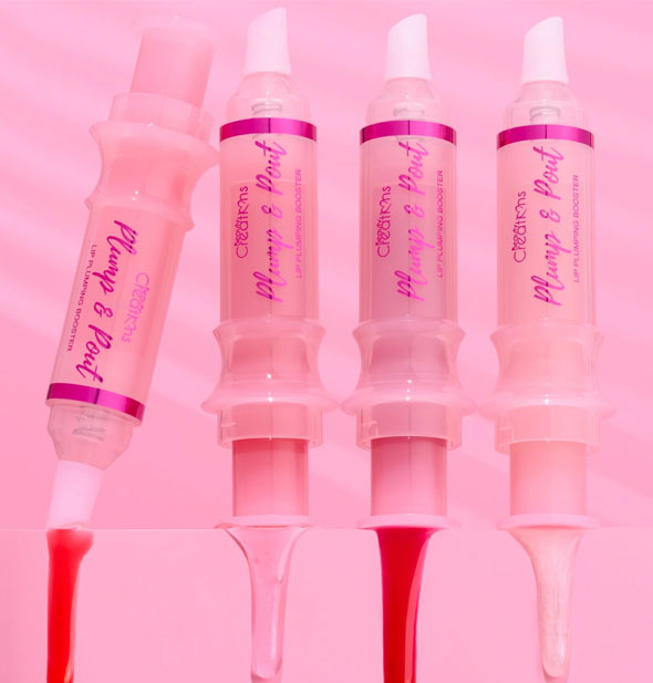 Four syringe-shaped tubes of Plump & Pout lip gloss with samples of each shade dripping down the side of a pink pedestal prop