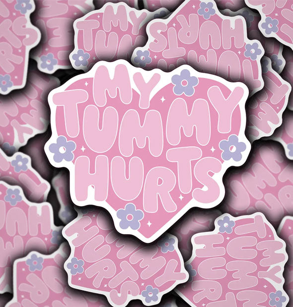 Grouping of heart-shaped stickers that say, "My tummy hurts" in bubble lettering accented with periwinkle daisies