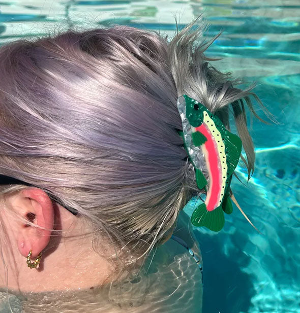 Model in a swimming pool wears a rainbow trout claw clip in a swept-back hairstyle