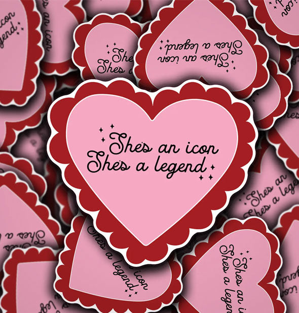 Grouping of pink heart-shaped stickers with red frilly borders each say, "She's an icon, She's a legend" in black script with small black star accents