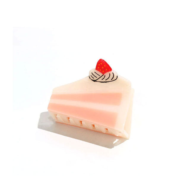 Hair clip designed and painted to resemble a slice of pink cake with a strawberry and whipped cream on top
