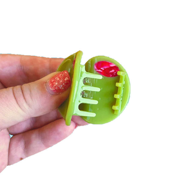 Model holds open a green olive hair clip