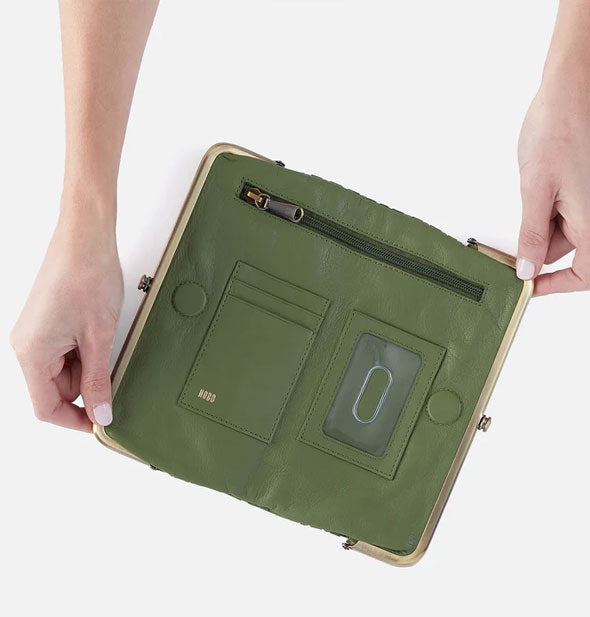 Model's hands hold open a green leather wallet to show storage compartments inside