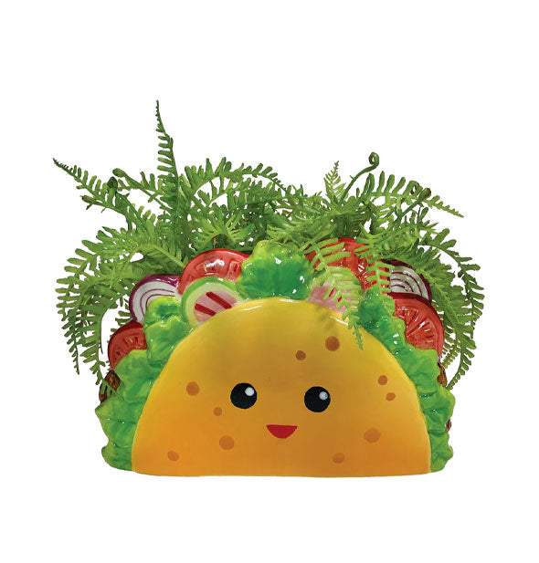Ceramic planter designed and painted to resemble a stuffed taco with smiling tortilla shell holds a fern