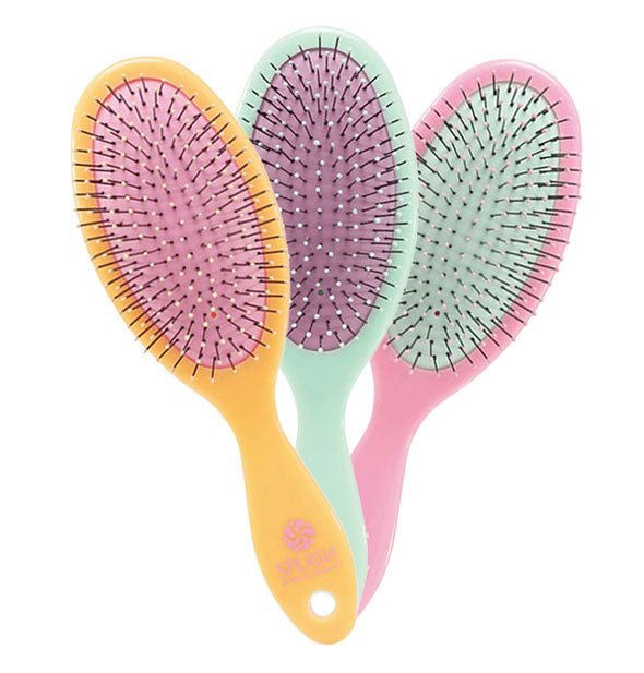 Three fanned-out Cricket Splash Detangling Brushes: one orange with pink cushion, one mint with purple cushion, and one pink with mint cushion