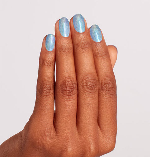 Model's hand wearing a shimmery holographic shade of blue nail polish