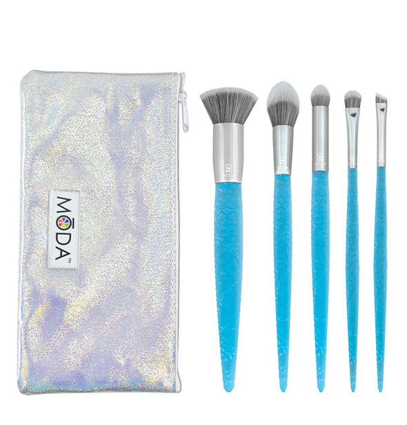 Five makeup brushes with sparkly blue handles next to a silvery iridescent Moda storage pouch