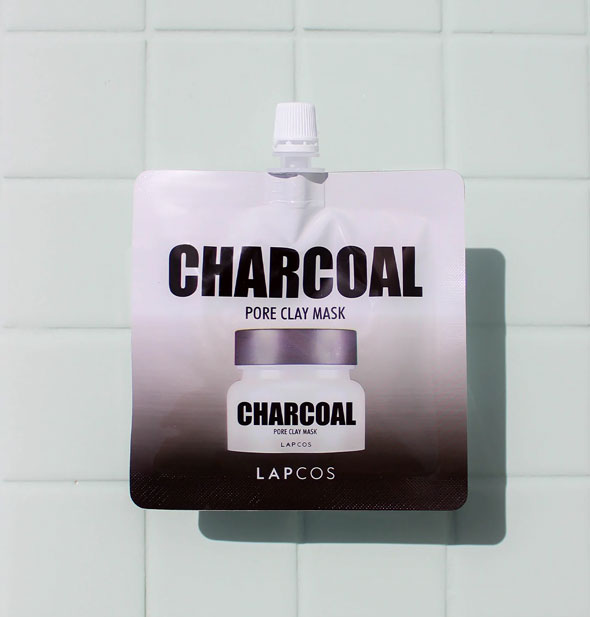 Packet of Charcoal Pore Clay Mask by LAPCOS with spout rests on a tiled surface