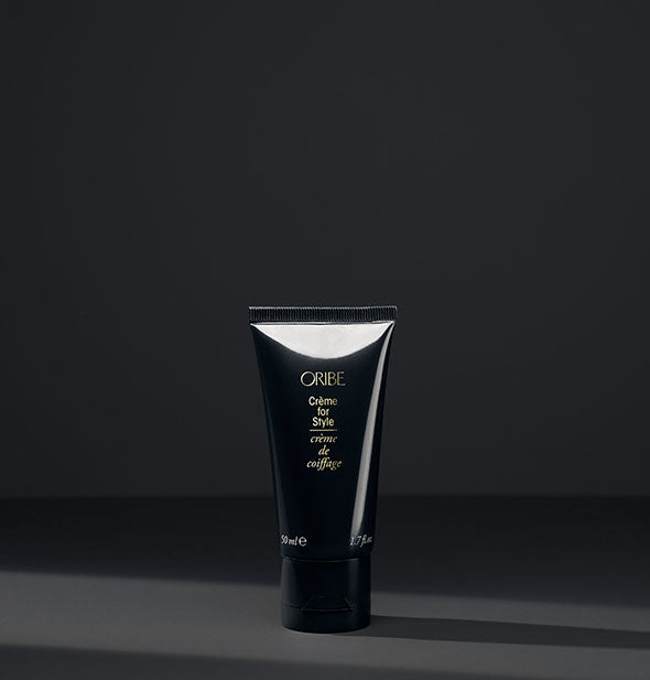 Small black bottle of Oribe Crème for Style on dark gray background