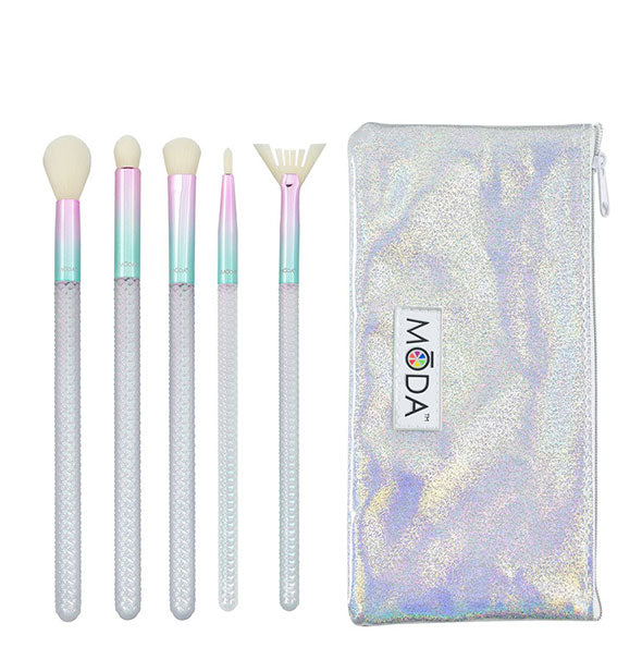 Five makeup brushes with metallic pink-to-green ombré ferrules and faceted iridescent handles next to silvery iridescent Moda storage case