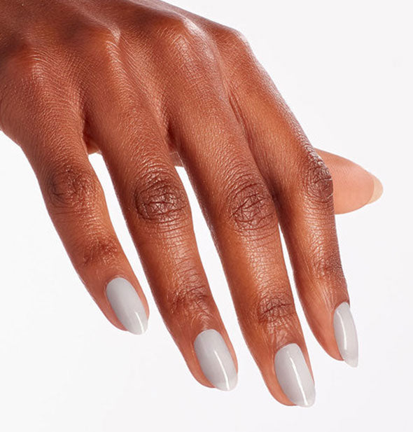 Model's hand wears a light, purplish gray shade of nail polish