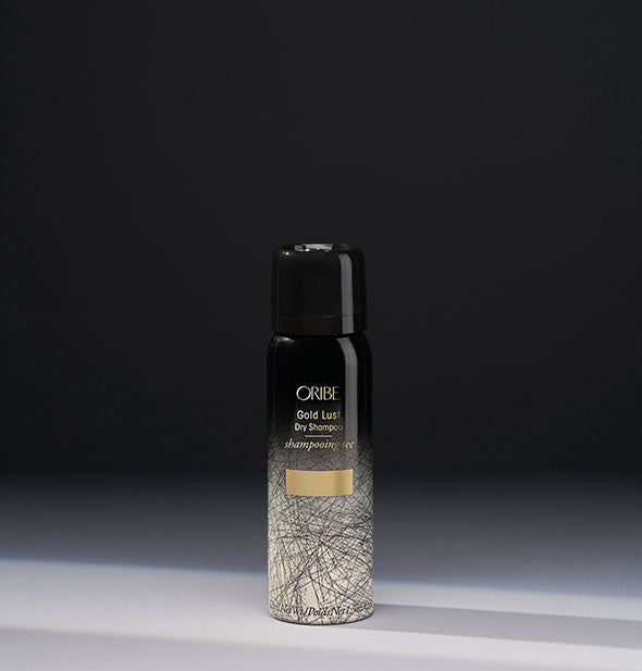 Small black and gold can of Oribe Gold Lust Dry Shampoo on dark gray background