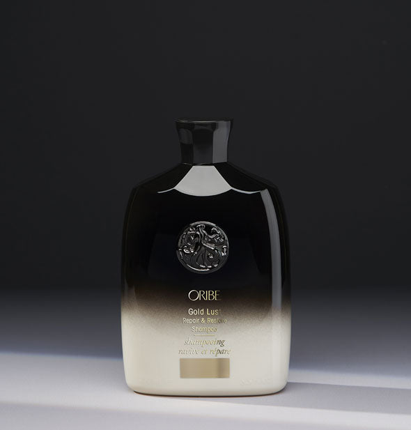 8.5 ounce black-to-white bottle of Oribe Gold Lust Repair & Restore Shampoo on gray background