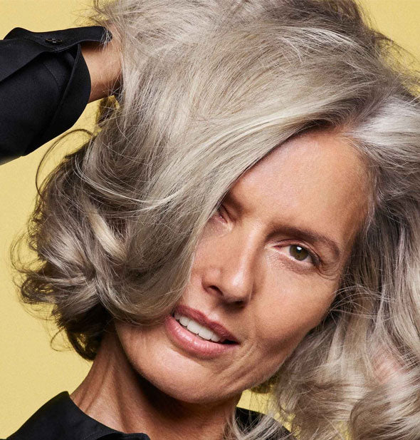 Model with healthy-looking gray hair demonstrates the effects of using Oribe's Hair Alchemy products