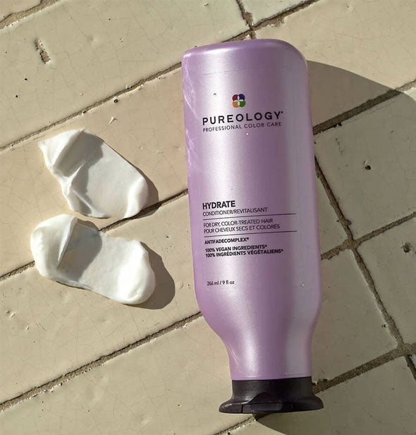 Pureology Hydrate Conditioner sits on a tiled surface next to sample product swabs