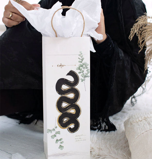 Model removes tissue paper from an Inky Path wine bottle gift bag