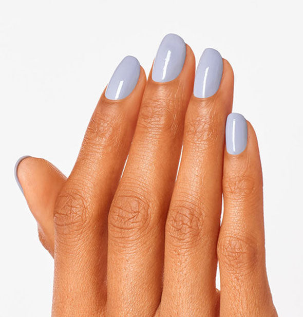 Model's hand wears a periwinkle gray-blue shade of nail polish