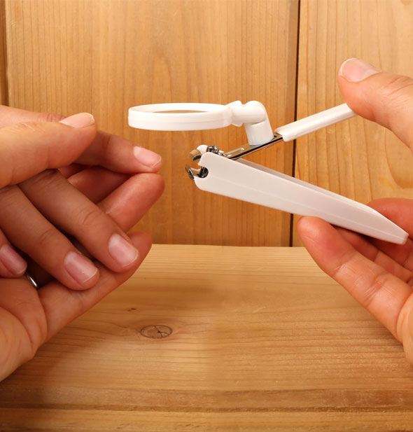 An adult demonstrates use of a magnifying nail clipper on a child's hand