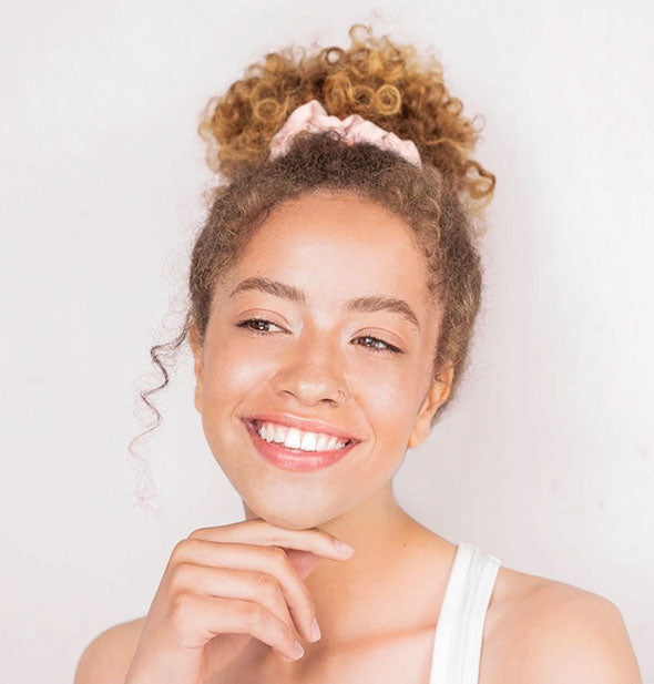 Smiling model wears a satin scrunchie in an updo