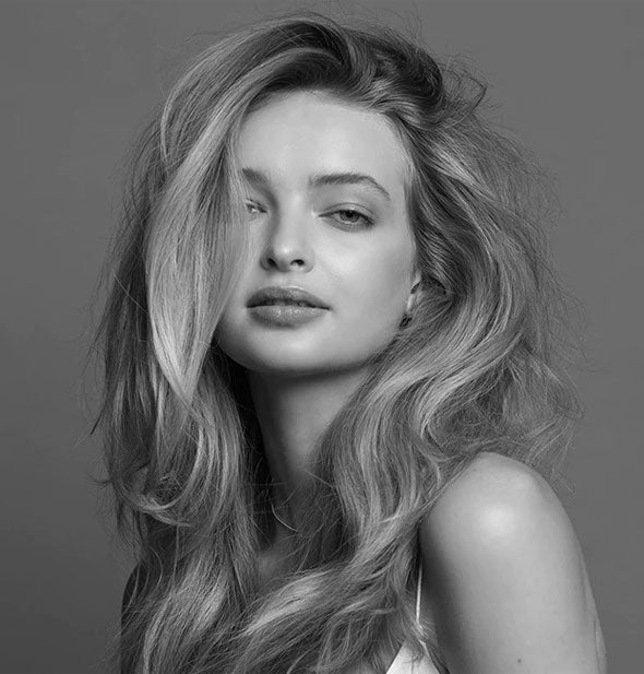 Model with full-looking hair demonstrates the results of styling with Bumble and bumble Thickening Full Form Soft Mousse