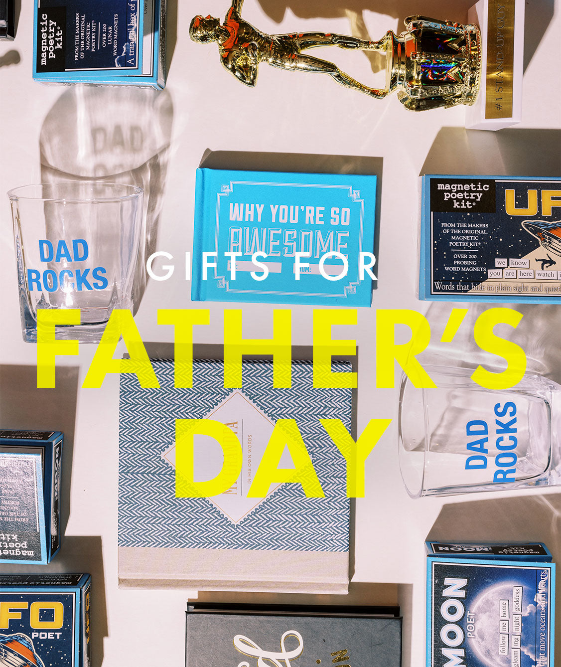 Gift items for dads including a trophy, book, and rocks glass with white and yellow lettering overtop that read, "Gifts for Father's Day"