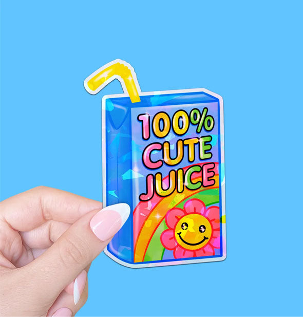 Model's hand holds a sticker designed as a blue juice box with a yellow straw and rainbow and daisy graphics that says, "100% Cute Juice" in colorful lettering