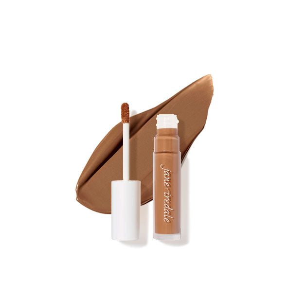 Clear tube of Jane Iredale concealer with doe foot applicator cap removed rests on top of an enlarged sample product application in shade 12W