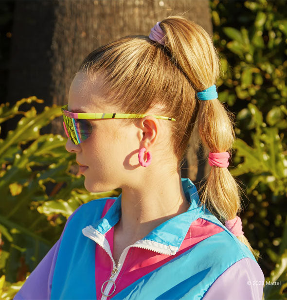Model wears pink and blue hair ties spaced out along the length of a high ponytail