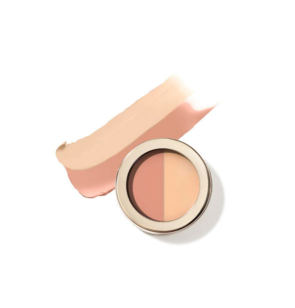 Round pot of Jane Iredale two-tone Circle\Delete Concealer with gold rim and sample product application behind in shade #1 - Light/Medium Peach