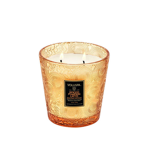 2-wick candle burning in a slightly tapered embossed orange glass container with black label.