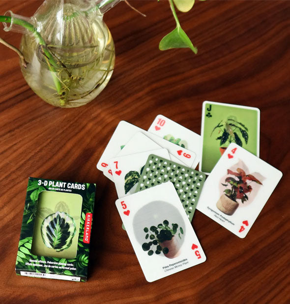 A smattering of 3-D Plant Cards on a wooden tabletop with a pothos cutting in water
