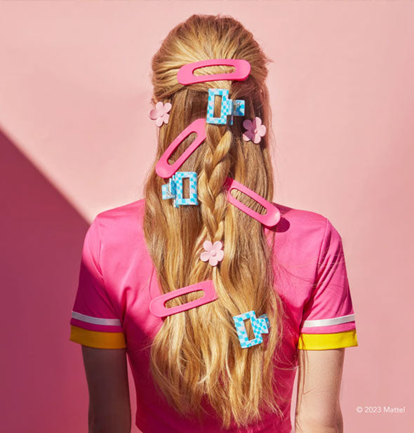 Model wears an assortment of pink and blue hair clips in a half-braided long style
