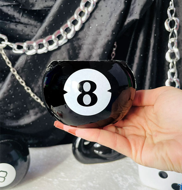 Model's hand holds an 8 ball ashtray for scale