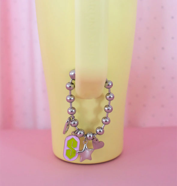 Silver 90s ball chain charm attached to the handle of a yellow Stanley cup