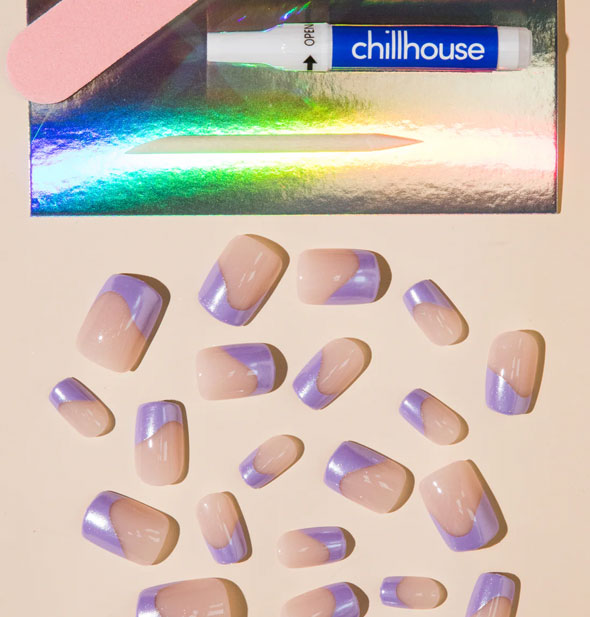 Contents of the AI Supernova Chillhouse press-on nail kit: pink file, glue tube, wooden cuticle pusher, and scattered nails in varying sizes featuring a lopsided metallic purple French tip design